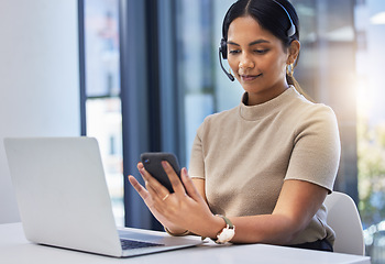 Image showing Call center, woman and typing on smartphone at laptop in office of customer service, CRM consulting and help desk. Telemarketing, female consultant and mobile communication at computer on telecom app