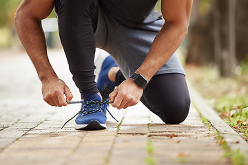 Image showing Man, hands and tying shoe in park for running, fitness or cardio workout and exercise in the outdoors. Hand of male person, runner or athlete tie shoes and getting ready for sports training in nature