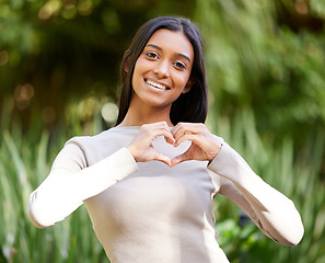 Image showing Portrait, smile and woman with heart hands in nature for love, care and affection. Face, love hand gesture and Indian female person with emoji for kindness, empathy or romance, support and trust.