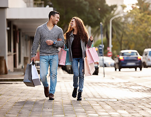 Image showing Happy couple, shopping bags and walking in city together for fashion, gift or buying in the outdoors. Man and woman in relationship with smile for customer discount, purchase or payment in urban town