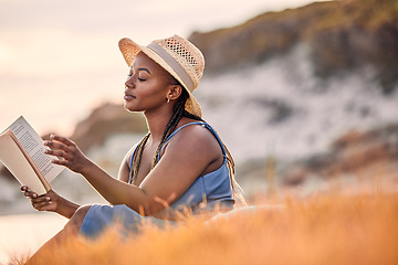 Image showing Mountain, cliff and woman reading a story while relaxing outdoor on the grass at sunset in summer. Freedom, travel and calm African female person enjoying a novel or fantasy book on hill with peace.