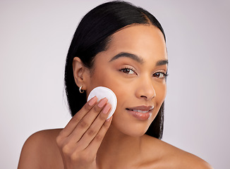 Image showing Happy woman, face and cotton pad in skincare for makeup removal against a grey studio background. Portrait of female person cleaning or wiping product and cosmetics with swab for facial treatment