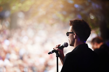 Image showing Charismatic frontman. A singer performing on stage at an outdoor music festival.