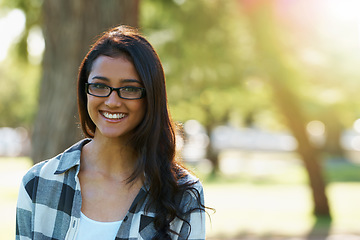 Image showing Relaxed beauty. A beautiful young woman wearing glasses standing in a park.