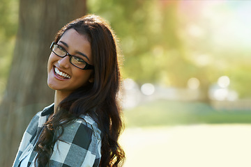 Image showing Casual charm. A beautiful ethnic woman standing in a park wearing glasses.