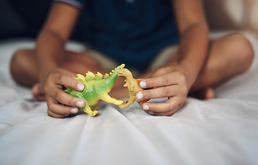 Image showing I wish dinosaurs still existed. Cropped shot of an unrecognizable boy playing with dinosaurs while sitting on his bed.