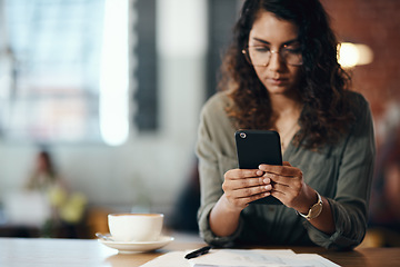 Image showing Its a freelancers world and were all living in it. Shot of a young woman using a smartphone while working in a cafe.