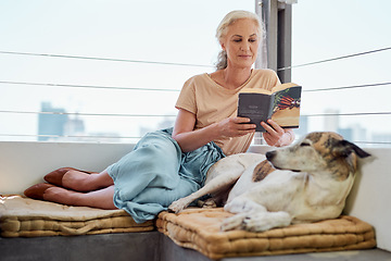 Image showing Next to dogs, books are my best friends. Shot of a mature woman reading a book on her balcony with her dog next to her at home.