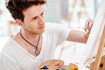 Image showing Everything you can imagine is real. Cropped shot of a handsome young artist sitting alone and painting during an art class in the studio.