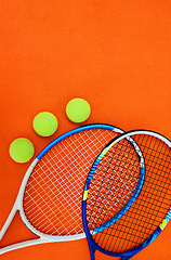 Image showing Who wants to serve. High angle shot of tennis essentials placed on top of an orange background inside of a studio.