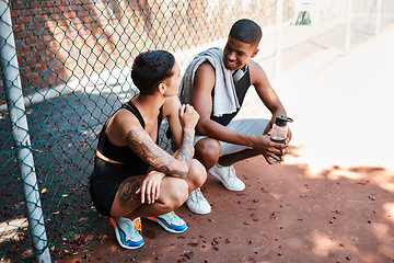 Image showing They share so much in common. Shot of two sporty young people chatting to each other against a fence outdoors.