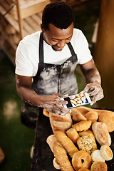 Image showing This picture is for todays online baking tips. Cropped shot of a male baker taking a picture on his cellphone of a selection of freshly baked bread.