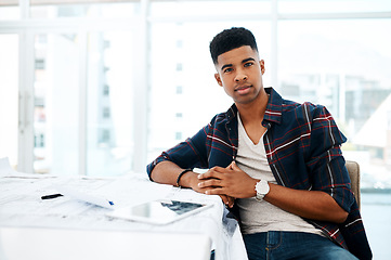 Image showing Dedicated to delivering the best quality designs. Portrait of a young man going over blueprints in a modern office.