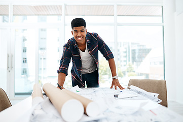 Image showing At the head of the design helm. Portrait of a young man going over blueprints in a modern office.