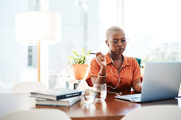 Image showing A goal is a dream with a deadline. Shot of a young businesswoman wearing earphones while working on a laptop in an office.