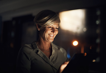 Image showing I found an app thatll make my job easier tonight. Shot of a mature businesswoman using a digital tablet in an office at night.