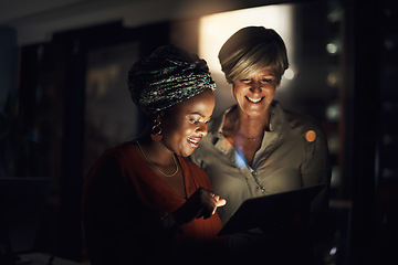 Image showing Optimising their time with technology. Shot of two businesswomen using a digital tablet together in an office at night.