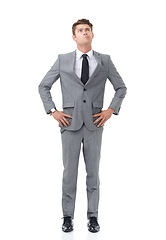 Image showing Ready to climb the corporate ladder. A young businessman standing with his hands on his hips looking upwards.