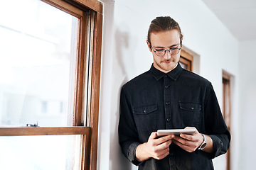 Image showing I can achieve anything. Cropped shot of a handsome young businessman standing and using a tablet in his office alone.