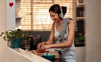 Image showing Music headphones, morning and woman cooking breakfast of healthy strawberry food at home. Kitchen, headphone and happy female person making snack with fruits while listening to audio, sound and radio