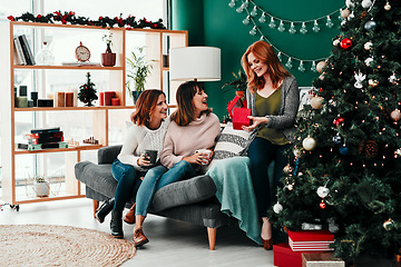 Image showing You guys shouldt have. Shot of three attractive middle aged women opening presents together while being seated on a sofa during Christmas time.