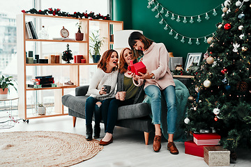 Image showing Thank you both very much. Shot of three attractive middle aged women opening presents together while being seated on a sofa during Christmas time.