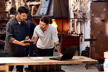 Image showing Have a look at this. Cropped shot of two handsome young using their digital devices while working together inside their workshop.