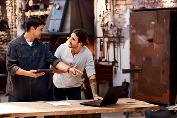 Image showing We work better as a team. Cropped shot of two handsome young using their digital devices while working together inside their workshop.