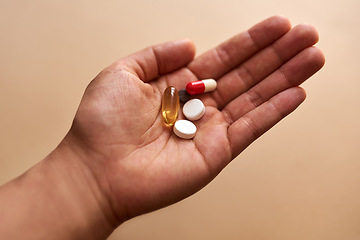 Image showing Some illnesses require a cocktail of pills. Studio shot of an unrecognisable woman holding a handful of pills against a brown background.