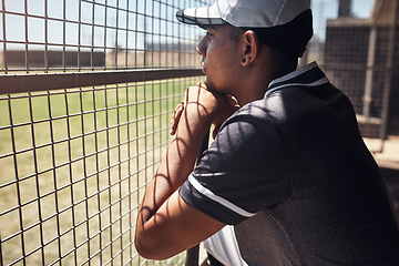 Image showing Nothing hypnotises him like baseball. Shot of a young man watching a game of baseball from behind the fence.