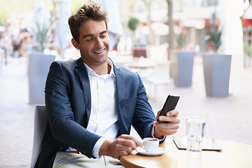 Image showing Shes on the way....Shot of a young businessman reading a text while sitting at an outdoor cafe.