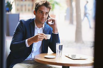 Image showing Business even when on break. Shot of a young businessman enjoying a cup of coffee and talking on the phone.