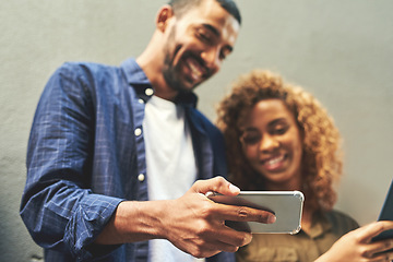 Image showing We love sharing our selfies on social media. Shot of a young couple looking at a smartphone together outside.