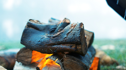 Image showing Bonfire circle, camp and outdoor in nature with stone, rock and safe on ground, grass and aerial closeup. Fire, flames and burn wood for heat, cooking or relax on lawn, field and woods for holiday