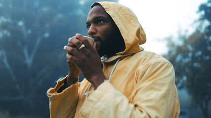 Image showing Coffee, morning and black man hiking in the forest with a blurred background of cold, winter weather. Thinking, raincoat and face of a young male hiker in the woods or nature to explore for adventure