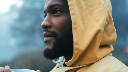 Image showing Coffee, morning and black man hiking in the woods with a blurred background of cold, winter weather. Thinking, raincoat and face of a young male hiker in the forest or nature to explore for adventure