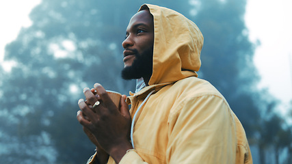 Image showing Coffee, morning and black man hiking in the forest with a blurred background of cold, winter weather. Thinking, raincoat and face of a young male hiker in the woods or nature to explore for adventure