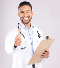 Image showing Happy asian man, doctor and portrait with thumbs up for healthcare approval against a grey studio background. Male person or medical expert smile with clipboard, like emoji or yes sign for success