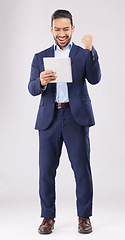 Image showing Happy businessman, tablet and fist pump for winning, promotion or bonus against a grey studio background. Excited asian man in celebration on technology for good news, lottery prize or sale discount