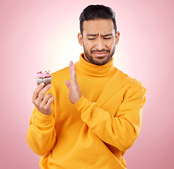 Image showing Man, cupcake and studio for diet choice, thinking or bad review for gluten allergy, health or pink background. Gen z guy, student or fashion model with muffin, cake or decision for nutrition feedback