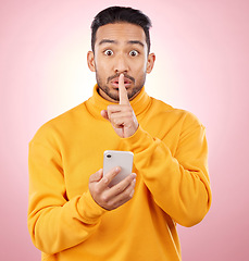 Image showing Man, phone and studio with finger, silence and sign language for secret promotion by pink background. Gen z guy, student or fashion model with smartphone, hand and lips for portrait, deal and sale