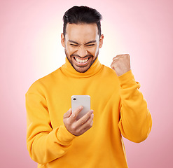 Image showing Winner, man and phone for success, yes and celebration of online news, social media or gaming results. Excited, mobile games and person reading notification or website bonus on pink studio background