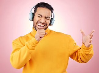 Image showing Asian man, headphones and listening to music while singing for karaoke against a pink studio background. Happy male person enjoying online audio streaming, sound track or songs with headset on mockup