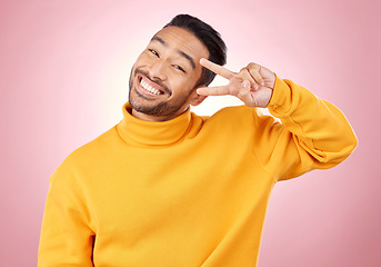 Image showing Smile, peace sign and portrait of man in studio for support, kindness and happy. Emoji, happiness and thank you with face of person on pink background for mindfulness, vote and v hand gesture