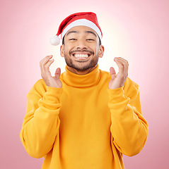 Image showing Portrait, excited and happy man with Christmas hat, fun and festive for holiday on pink background. Happiness, celebration and model with smile, santa cap and winter vacation fashion jersey in studio