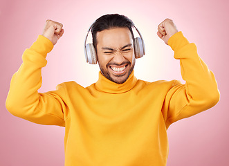 Image showing Music, headphones and man or winner success, yes and celebration for podcast, radio news and bonus. Motivation, power and happy person dance, listening to audio and excited on studio pink background