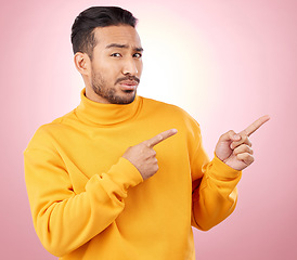 Image showing Pointing finger, confused man and portrait in studio with announcement, promotion or decision. Face of serious male asian model with hands for marketing sale, doubt or presentation on pink background