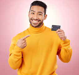 Image showing Man, pointing and credit card with finance, payment and loan, budget and fashion sale on studio pink background. Portrait, banking and happy asian person or gen z with retail transaction or shopping