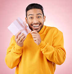 Image showing Young man, gift box and studio portrait with excited smile, ribbon and open for celebration by pink background. Asian gen z student, present or prize for giveaway, competition or package for party