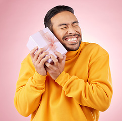 Image showing Man, excited winner and gift box, birthday celebration and prize, giveaway or shopping on pink background. Happy person with present, ribbon package and retail sale or competition love in studio